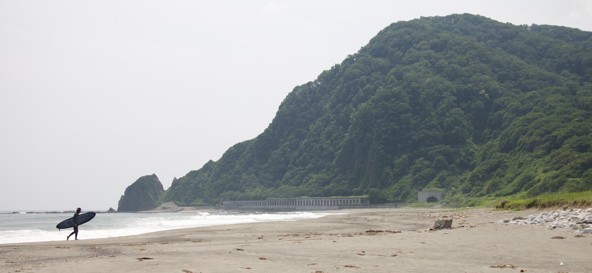 海岸を歩くサーファー