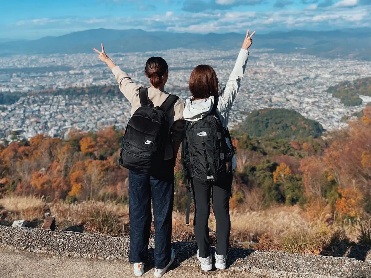 山でピースをする人物２人の後ろ姿