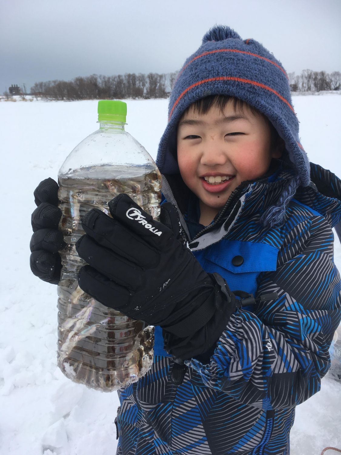 ワカサギの入ったペットボトルを持つ子供