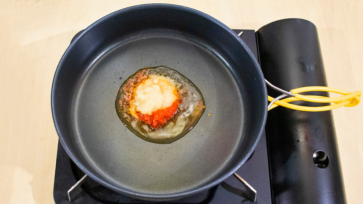 フライパンでごま油、豆板醤、おろしにんにく、おろししょうがを熱する