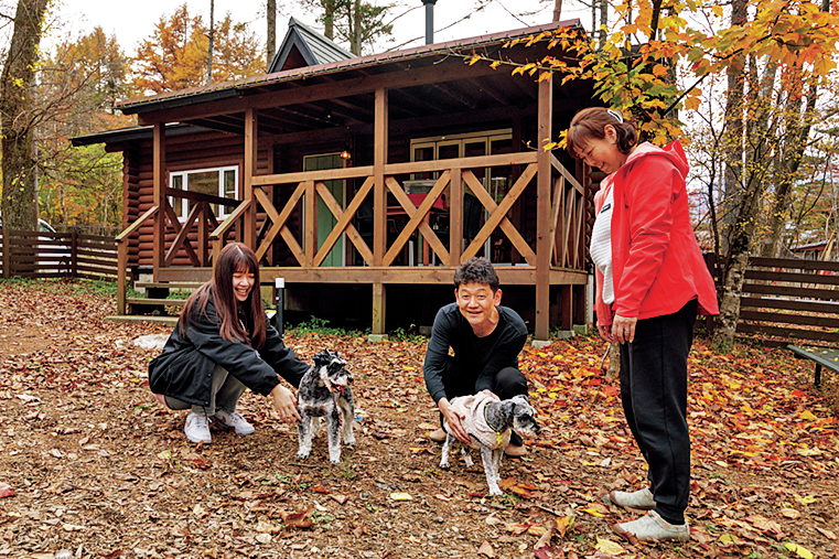 コテージ前で犬と遊ぶ人々