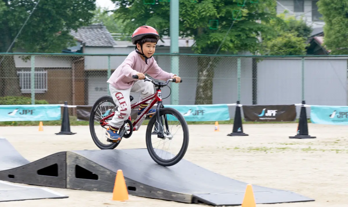 障害物を自転車で乗り越える子ども